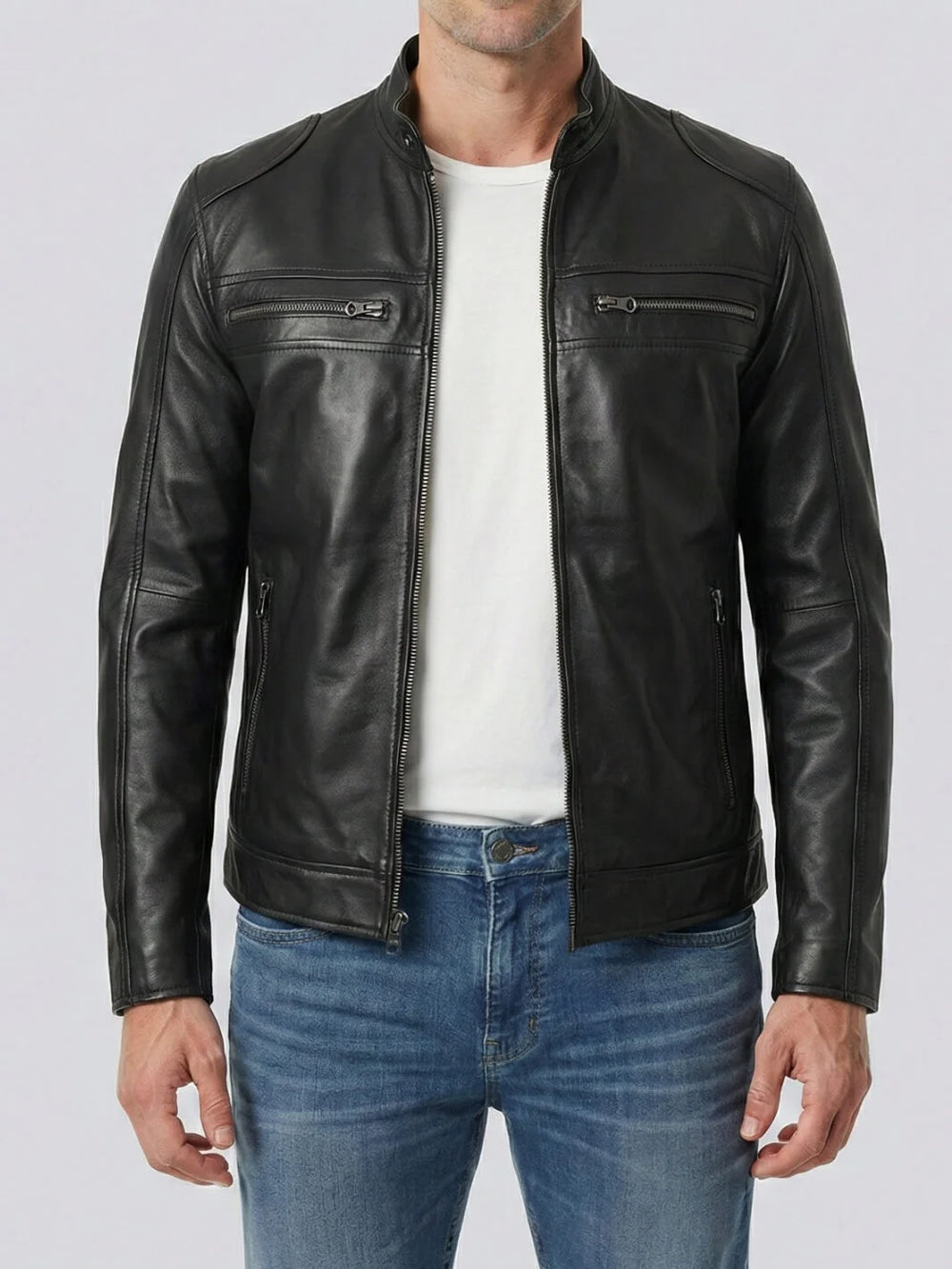 Man wearing a black leather jacket over a white shirt and blue jeans on a light gray background